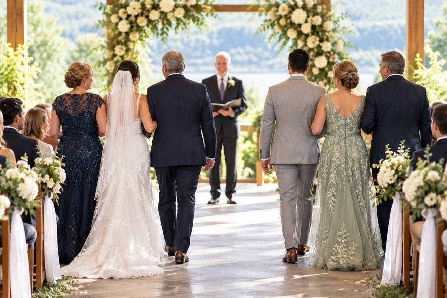 A bride being escorted down the aisle by a parent