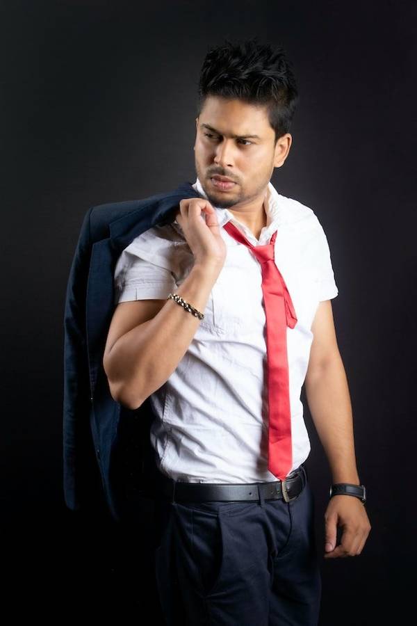 A man in a white shirt and red tie with his jacket over his shoulder