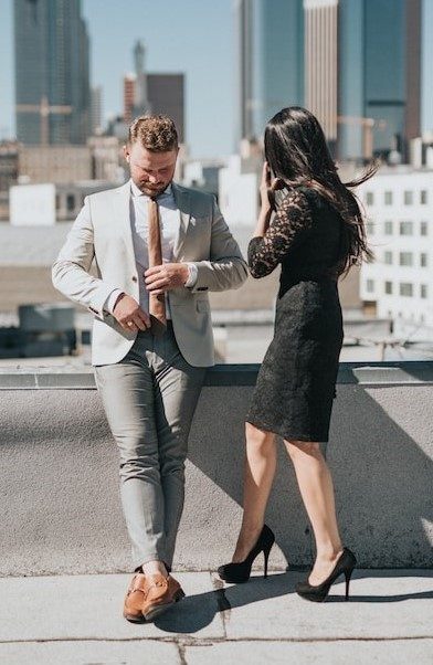 A groom in a light gray suit and a bride in a black lace dress on a rooftop
