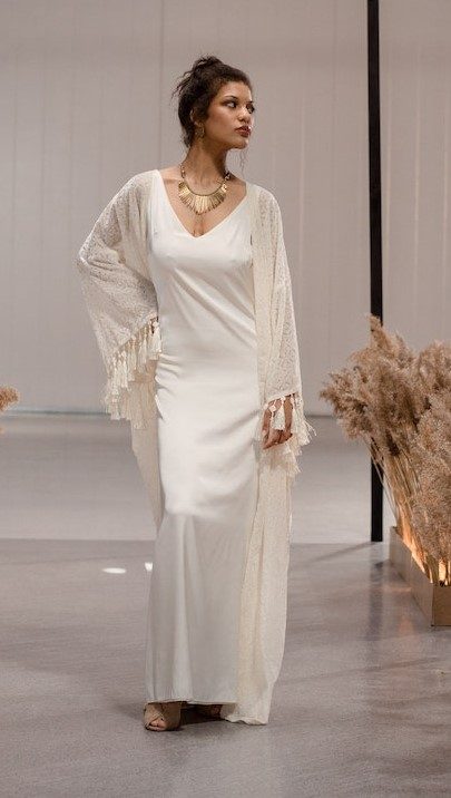 A woman in a white satin gown with a fringed lace wrap