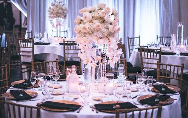 A tall centerpiece of blush roses and white orchids on a round reception table