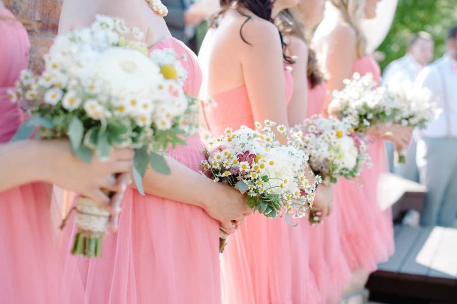 Bridesmaids in coral dresses holding wildflower bouquets