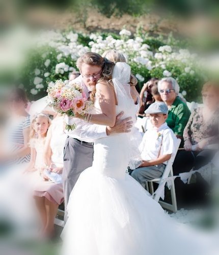 A father embracing his daughter at the end of the aisle