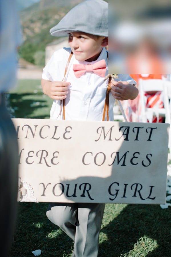 A young ring bearer carrying a sign down the aisle