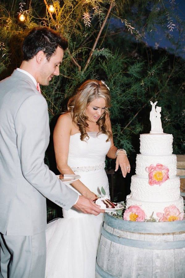 A couple cutting their wedding cake at night under string lights