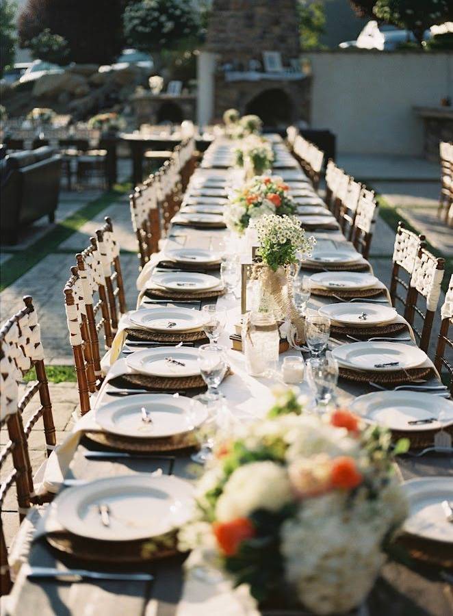 A long outdoor reception table set with flowers and candles