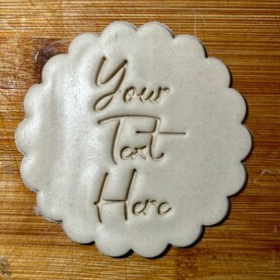 A scalloped sugar cookie stamped with custom text