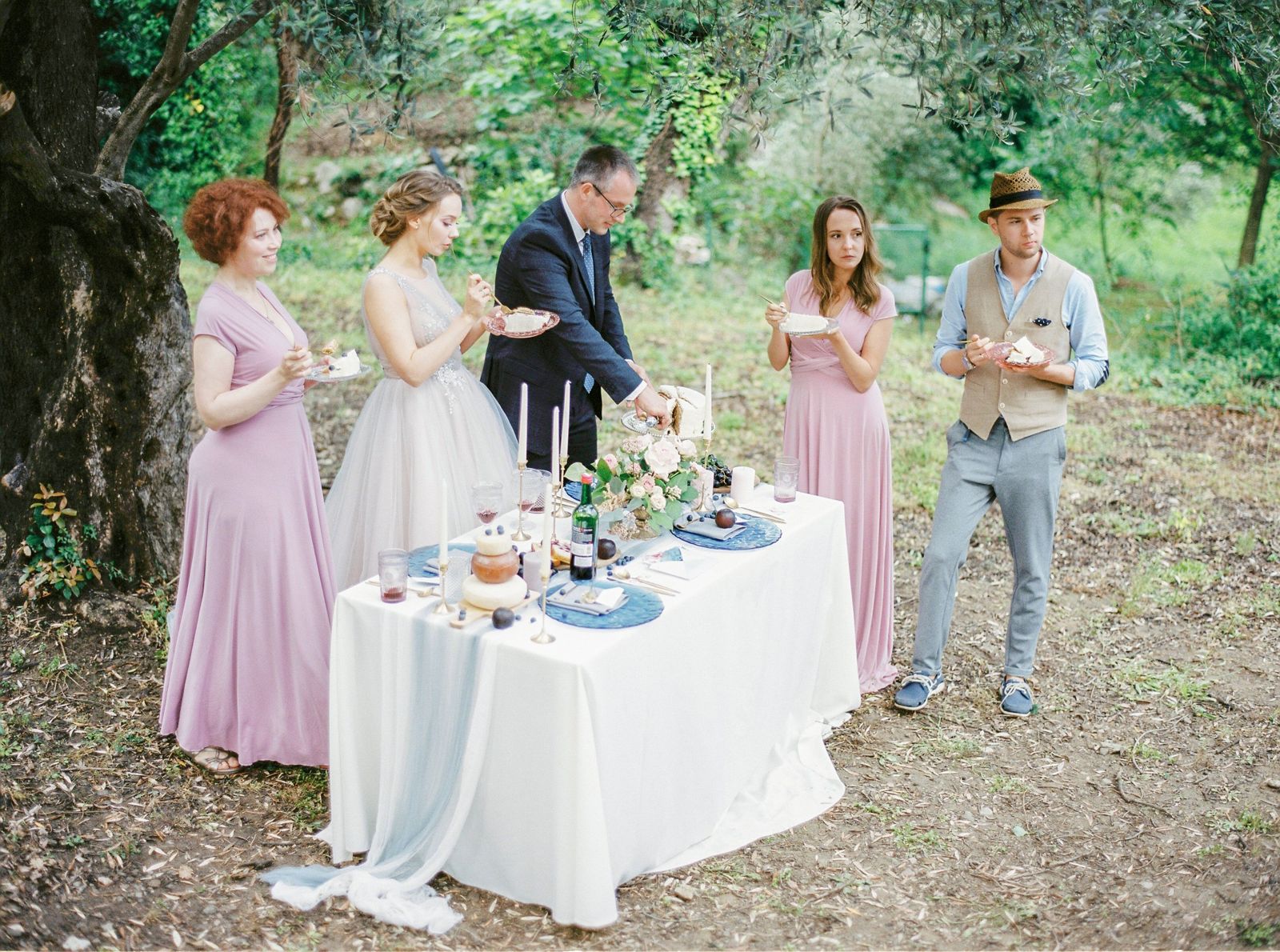 Family and friends gathered around the couple at a small outdoor wedding table in a garden