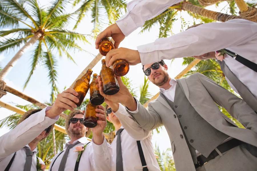 Groomsmen raising beer bottles together for a wedding toast